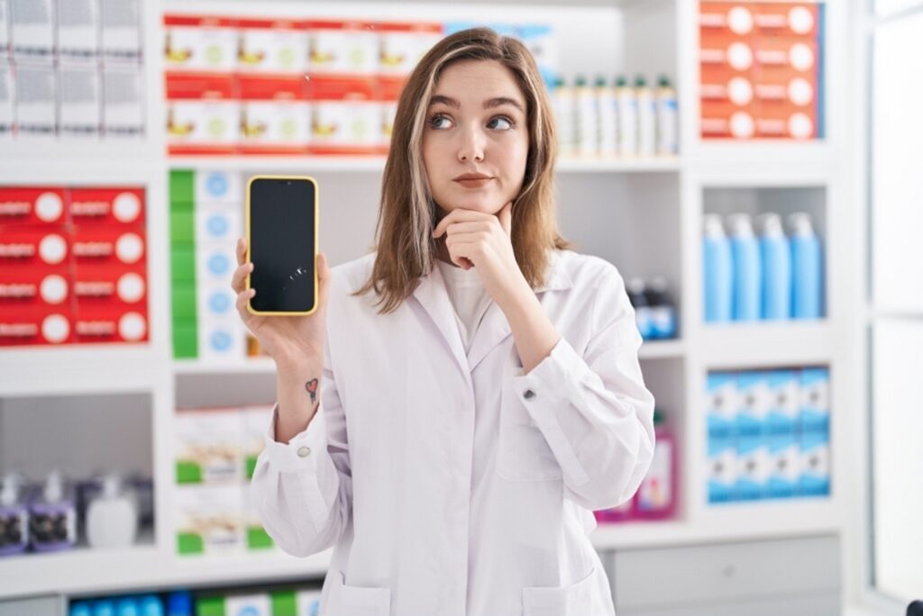stock-photo-blonde-caucasian-woman-working-at-pharmacy-drugstore-showing-smartphone-screen-serious-face-2187033833-transformed